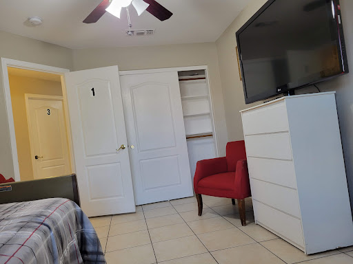 A cozy bedroom featuring a red chair, ample storage space with closets, and a mounted television.