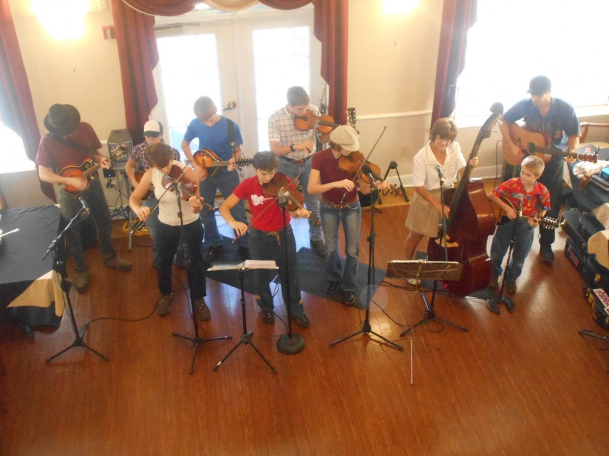 A group of musicians performing on stage with string instruments.