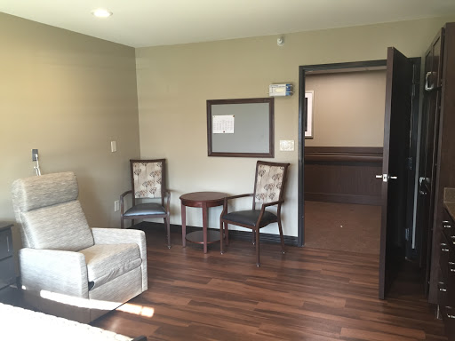 A cozy waiting room featuring two chairs and a small table, with wooden flooring and soft lighting.