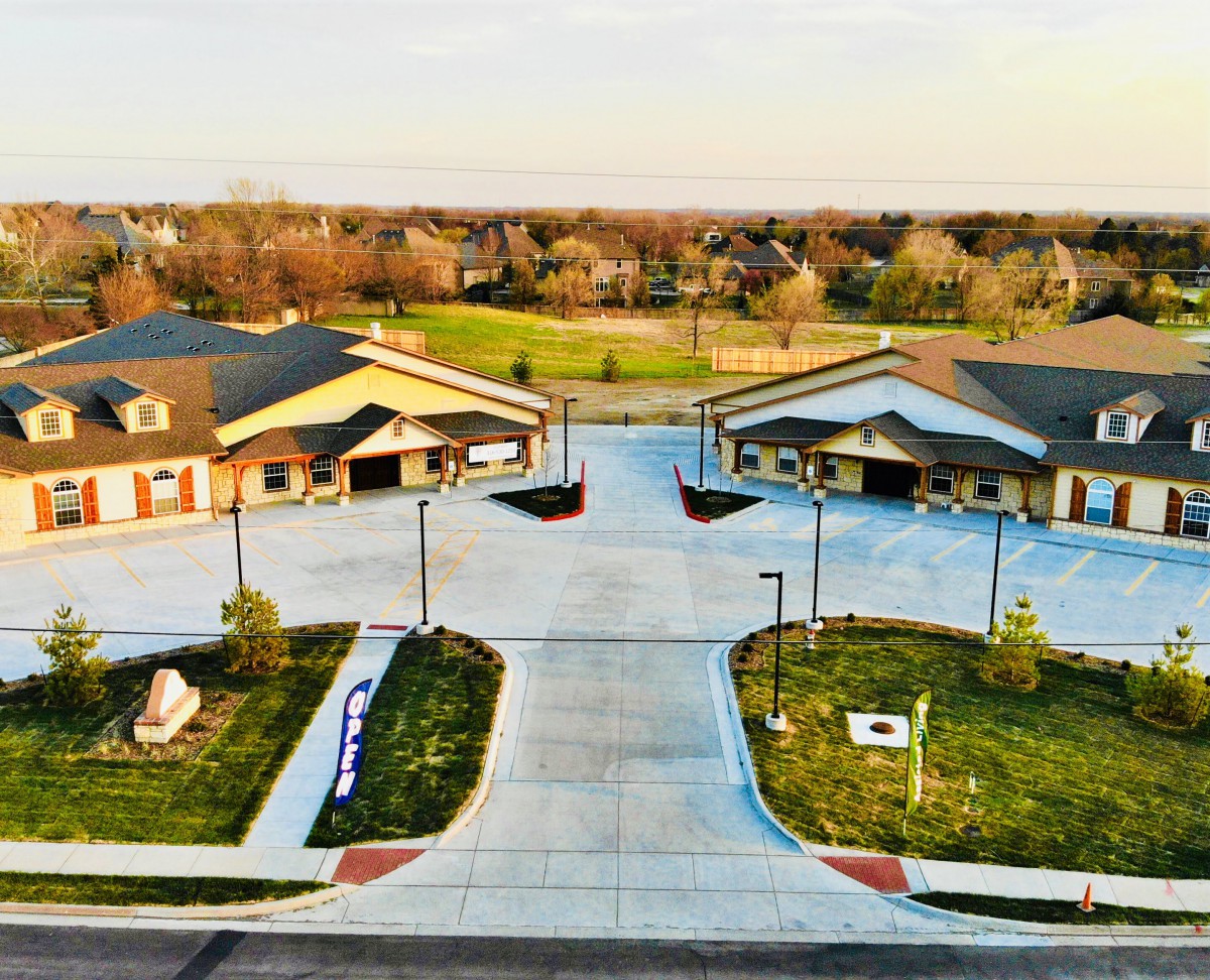Aerial view of suburban buildings with landscaped driveways and greenery.