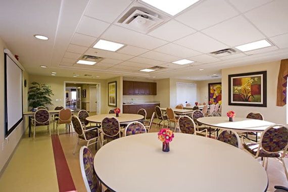 A spacious dining room with round tables and floral centerpieces.
