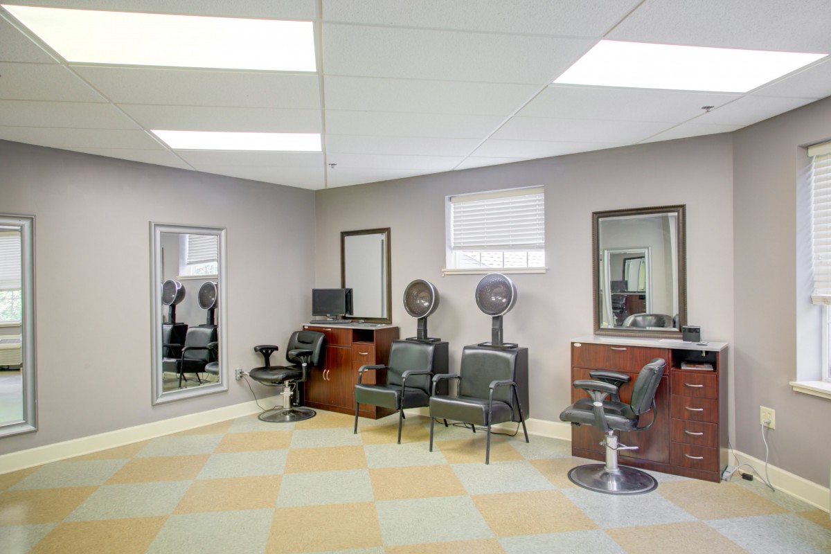 A modern hair salon with chairs, mirrors, and drying stations.