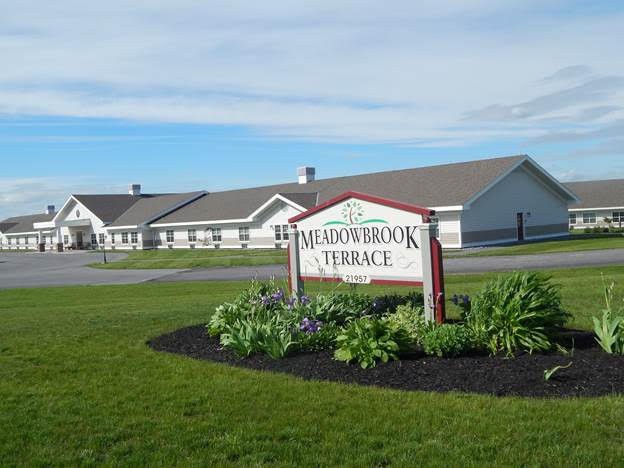 A landscaped view of a retirement home with a sign reading 'Meadowbrook Terrace'.