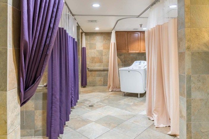 A spa therapy room with curtained sections and a massage tub.