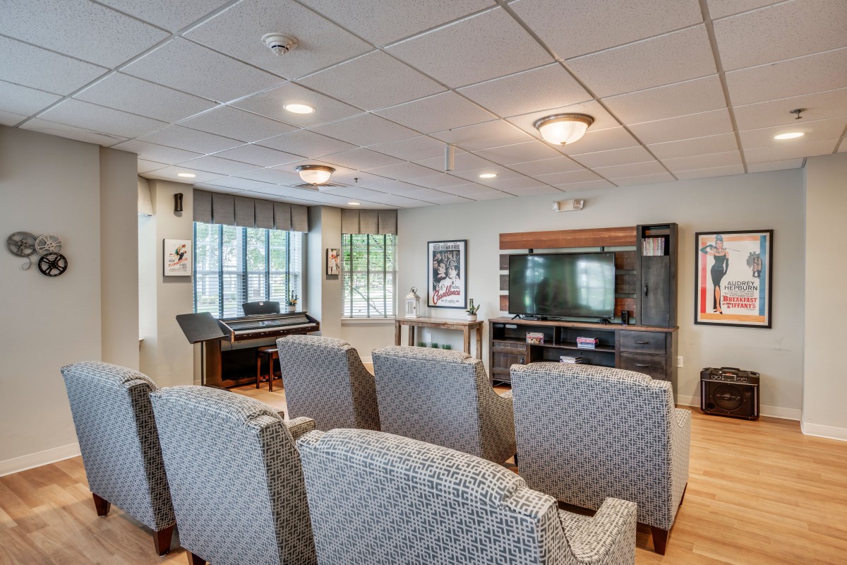 A cozy living room with a seating area, television, and piano.