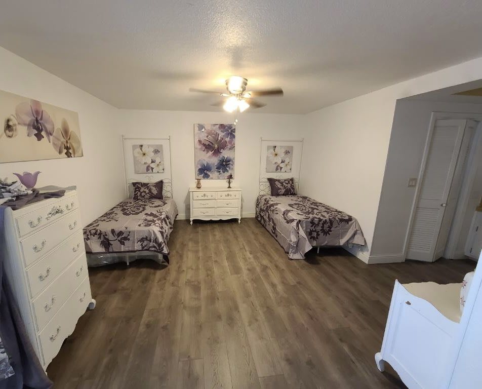 A bedroom with two twin beds, featuring floral decor and wood flooring.
