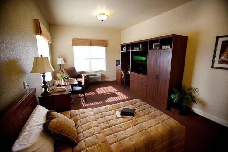 A cozy bedroom with a bed, desk, and TV stand.