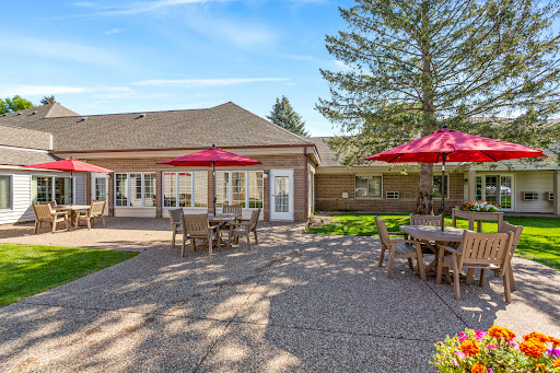 A sunny outdoor patio with dining tables and red umbrellas, perfect for enjoying a meal in the garden.