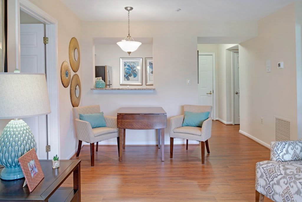A modern dining room with wooden flooring, featuring a small table and two chairs with blue cushions.