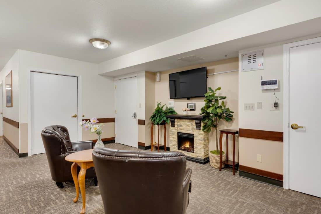 A cozy living room with armchairs, a fireplace, and a wall-mounted television.