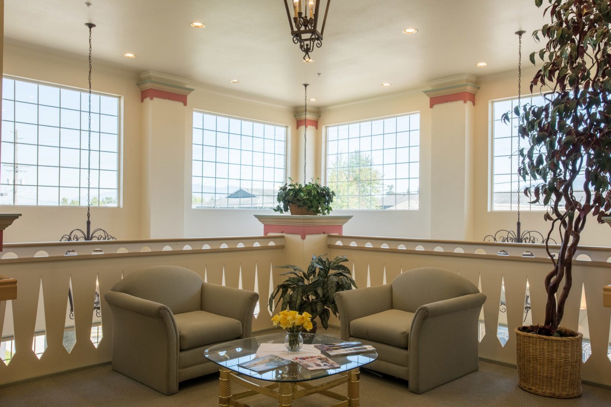 A cozy lounge area with two sofas, a glass coffee table, and large windows providing natural light.