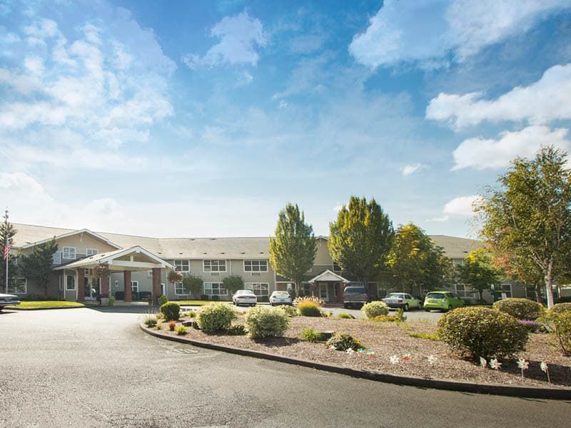 A large building with a surrounding parking lot and well-maintained landscaping on a clear day.