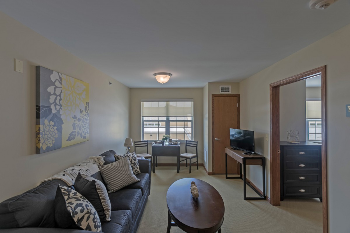 A cozy living room with a sofa, small table, and television near the window.