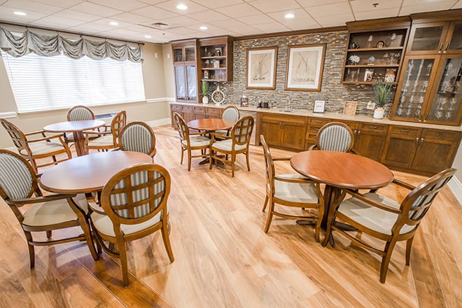 A cozy dining area with multiple tables and chairs, featuring a wooden floor and brick wall decor.