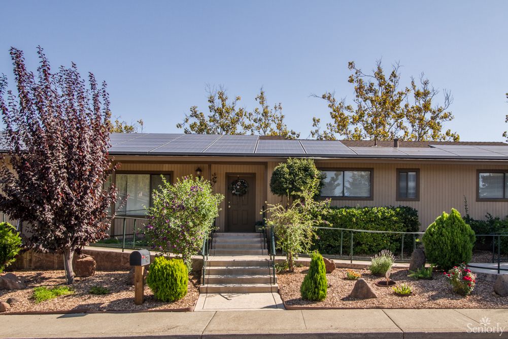 A well-maintained single-story house with a landscaped front yard featuring shrubs and trees.
