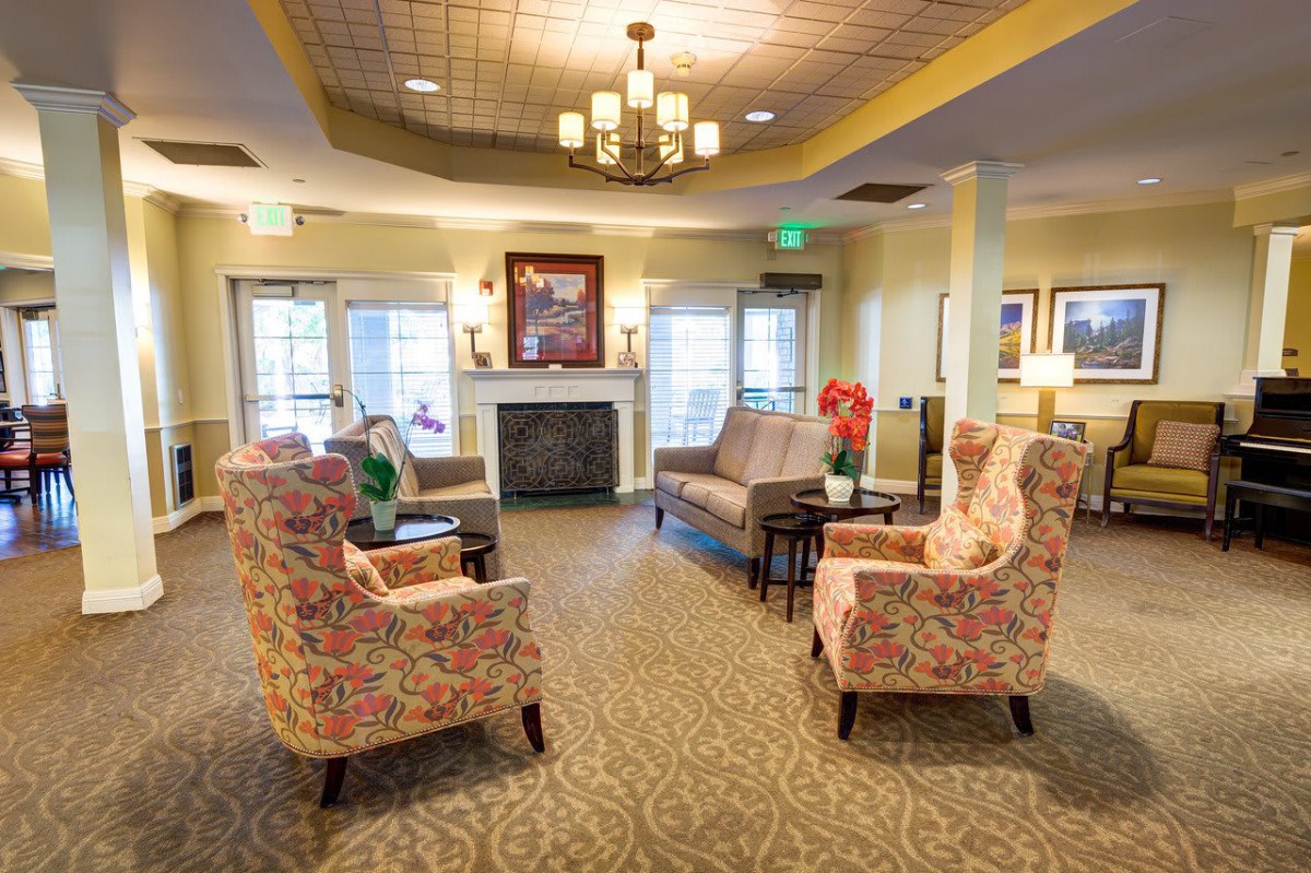 A cozy living room with floral armchairs, a sofa, and a fireplace.
