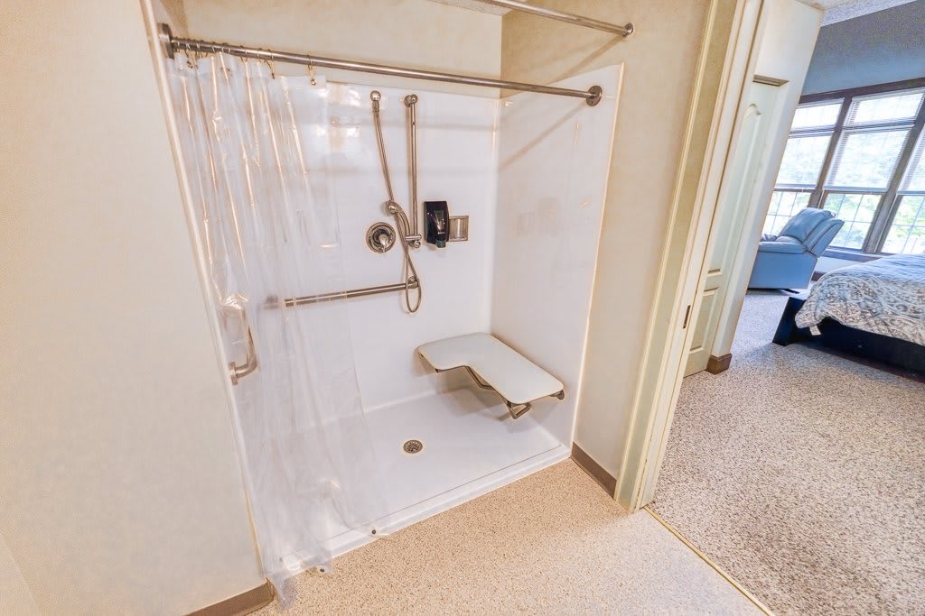 An accessible shower with a folding seat and grab bars, designed for ease of use.