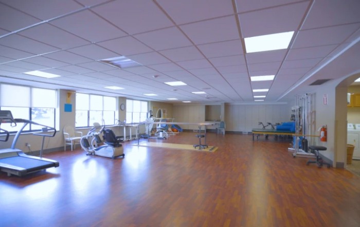 An empty rehabilitation center with exercise equipment and wooden flooring.