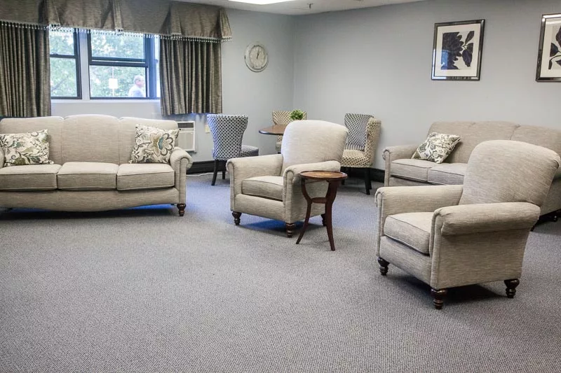 A cozy living room with beige sofas and chairs arranged around a small wooden table.