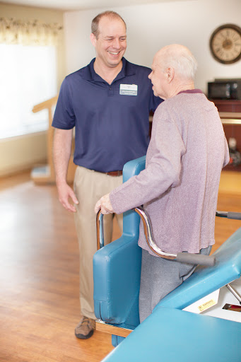 A caregiver assists an elderly person in a rehabilitation setting.
