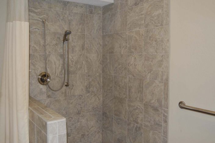 A tiled shower area with a handheld showerhead in a bathroom.