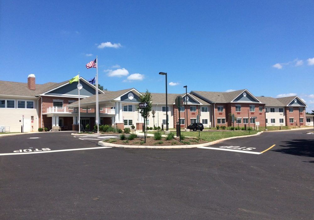 A view of a building with flags and a parking lot on a sunny day.