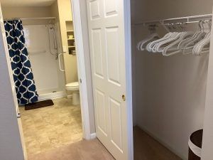 View of a closet with hangers near a bathroom.