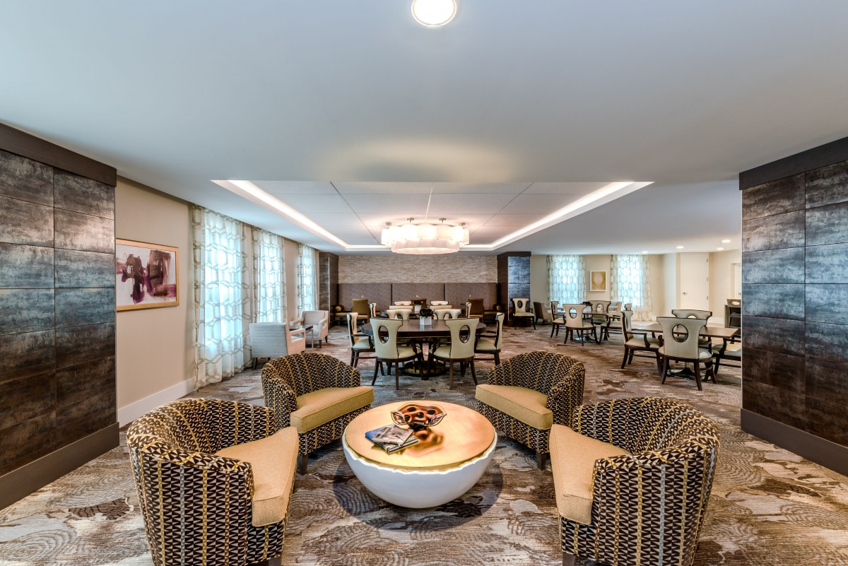 A modern living room with a central seating area, featuring a chandelier and stylish furniture.