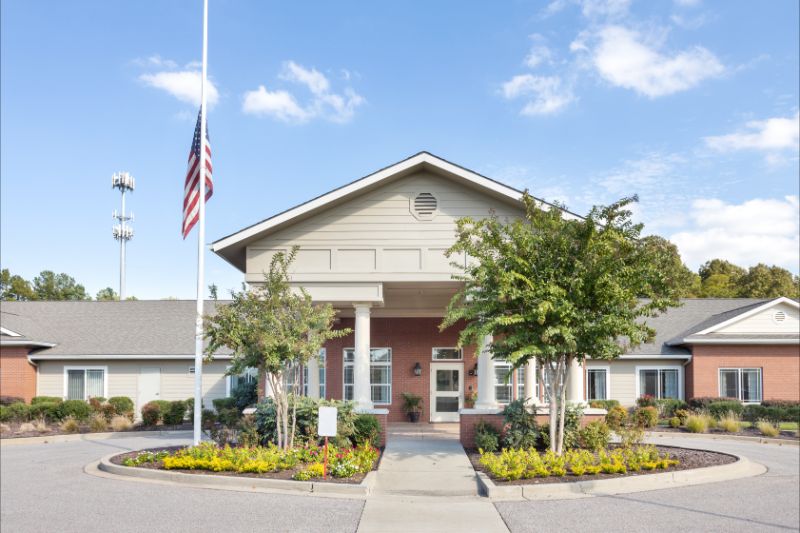 Front view of a building with an American flag and landscaped entrance.