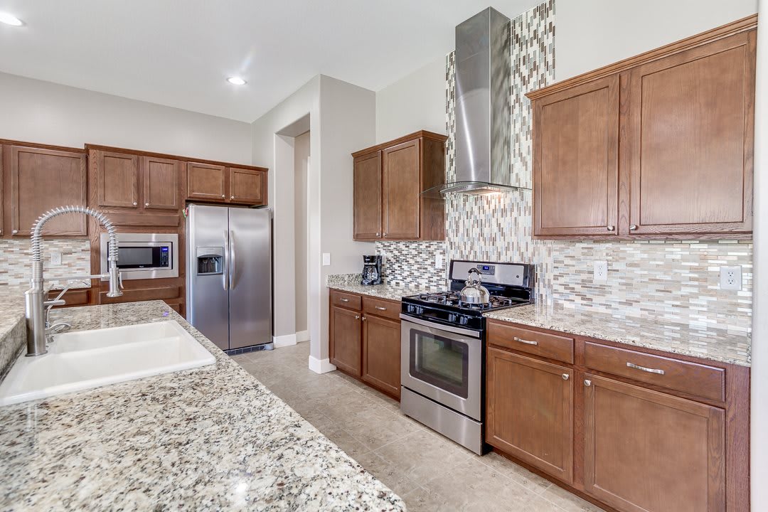 A modern kitchen featuring stainless steel appliances, wood cabinets, and granite countertops.