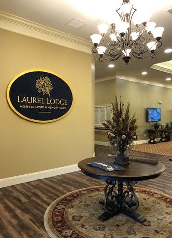 The elegant lobby of Laurel Lodge features a stylish chandelier and a decorative table with floral arrangements.