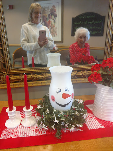 A cheerful holiday decoration featuring a smiling vase centerpiece, red candles, and lovely flowers.
