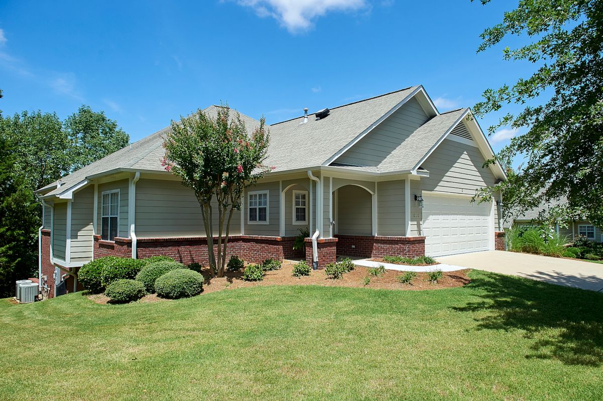 A suburban house with a well-maintained lawn and surrounding trees.
