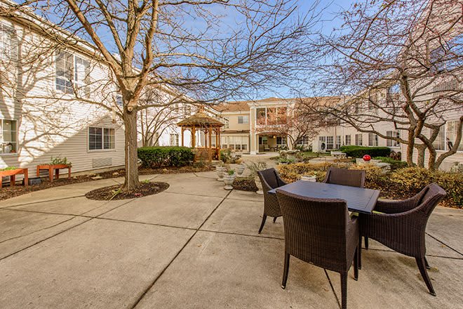 A sunny courtyard with patio furniture and surrounding buildings.