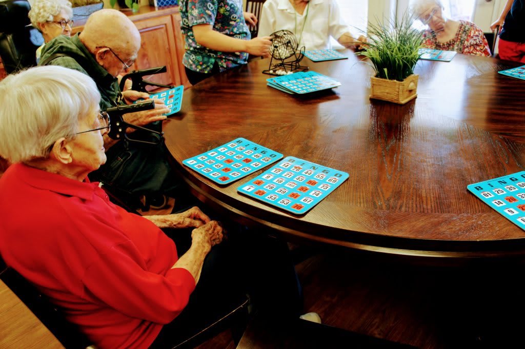 A group of seniors playing bingo at a round table.