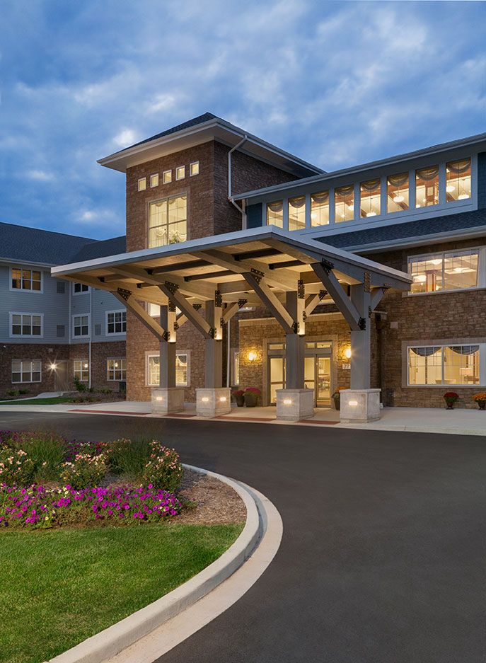A well-lit residential building entrance with landscaped surroundings during the evening.