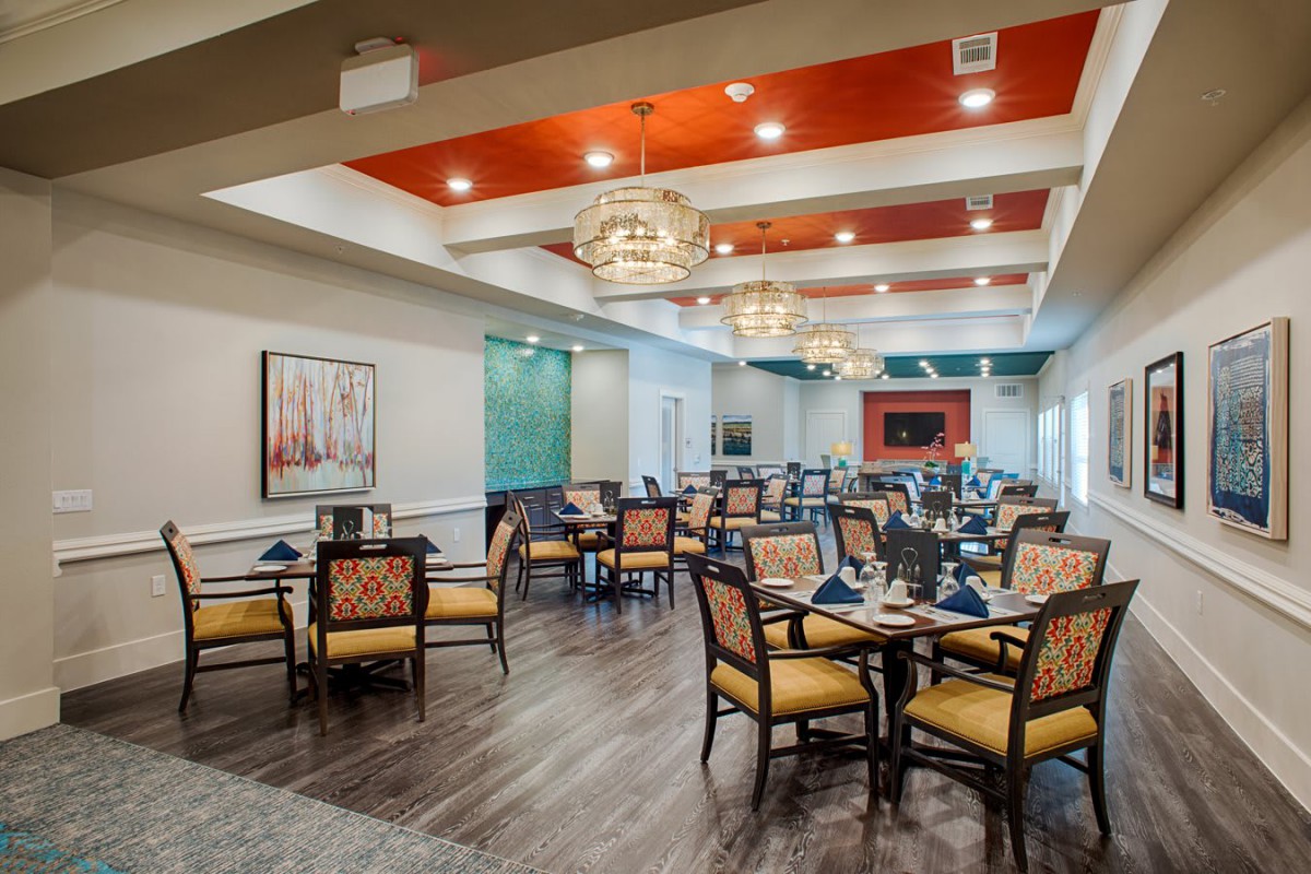 A modern dining room featuring elegant chandeliers and a spacious seating area with stylish decor.
