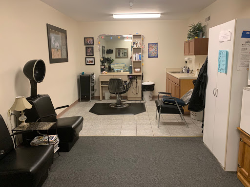 A cozy salon space featuring styling chairs, a large mirror, and a welcoming atmosphere.