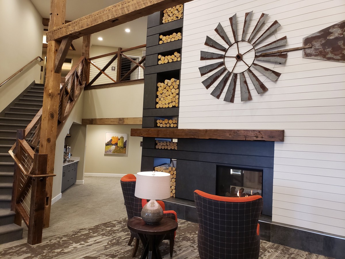 A cozy rustic living room featuring a fireplace, wooden beams, and windmill wall decor.