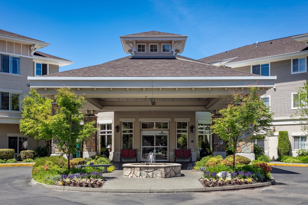 A well-landscaped entrance to a residential building under a clear blue sky.