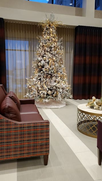 A cozy living room decorated for the holidays with a beautifully adorned Christmas tree and elegant furniture.