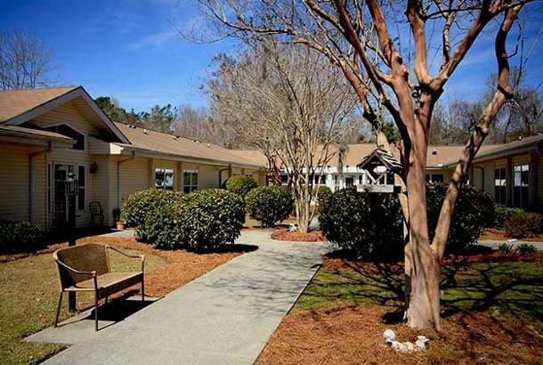 A peaceful garden pathway with a bench and trees lining a building.