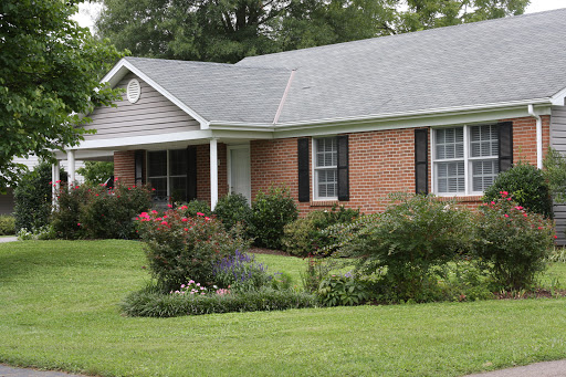 A charming single-story brick house with a well-maintained front yard and colorful landscaping.