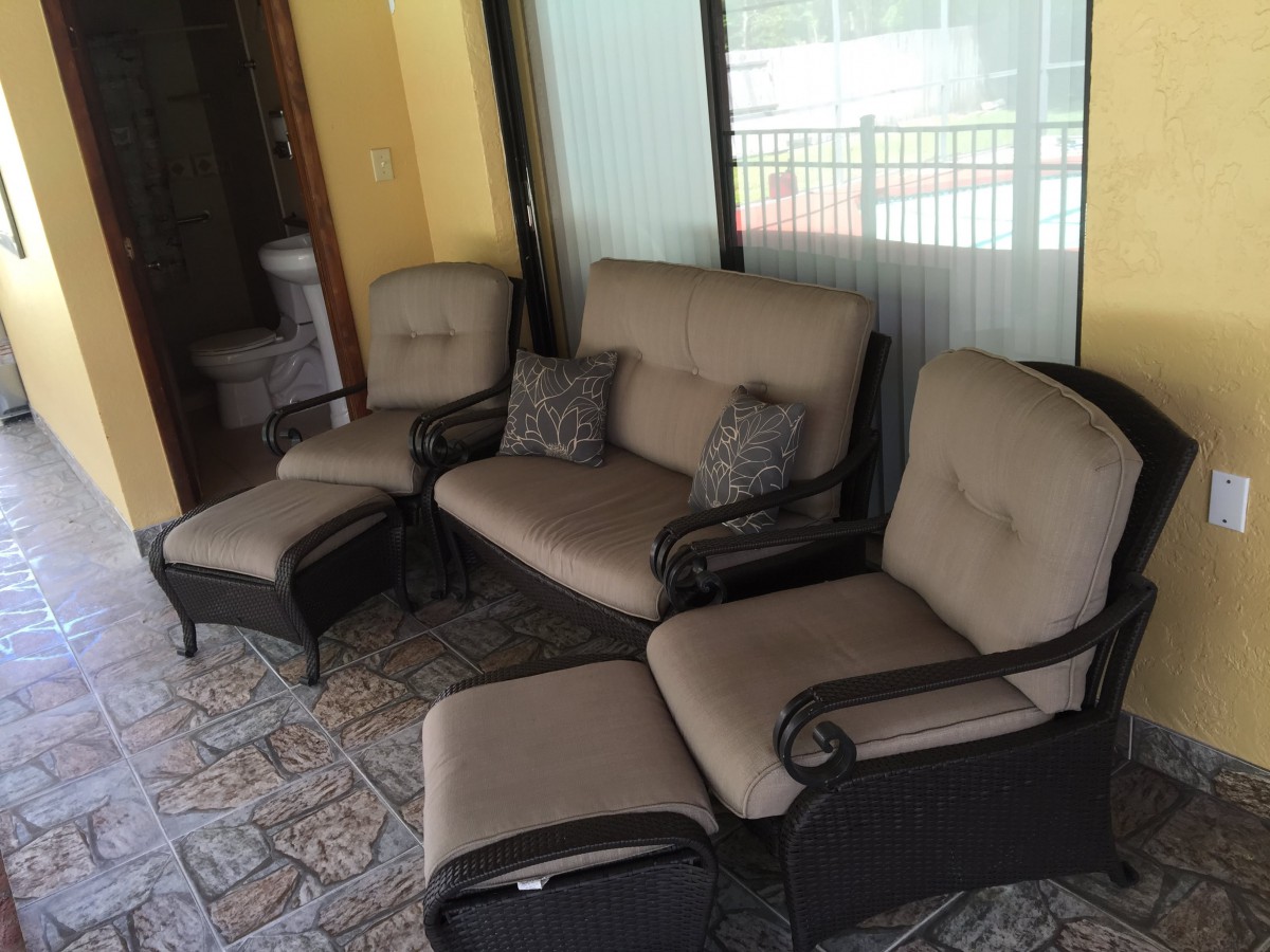A cozy outdoor seating area featuring a sofa and chairs with cushions on a tiled patio.