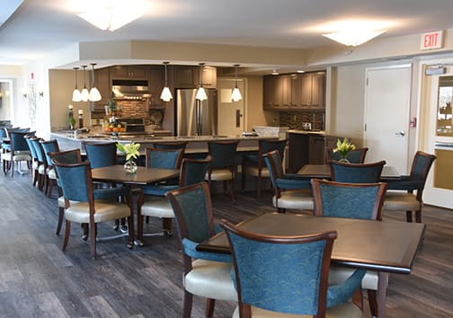 A modern dining area with tables and chairs, adjacent to a kitchen.