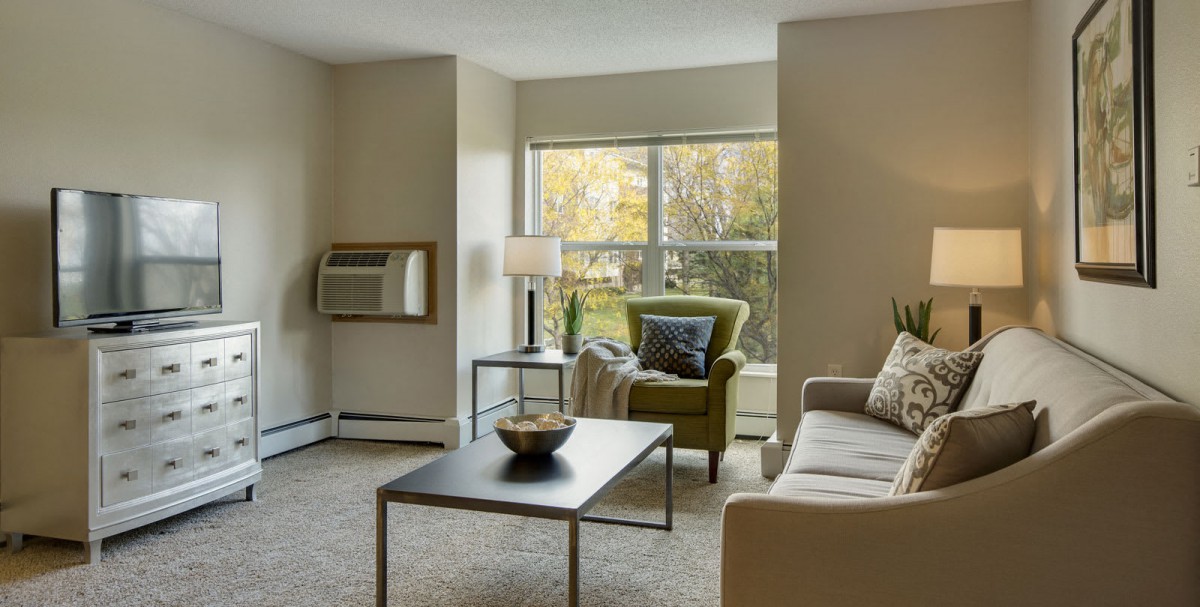 Cozy living room with a sofa, armchair, and large window.