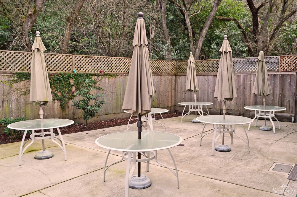 An outdoor patio area with several tables and umbrellas surrounded by a wooden fence.
