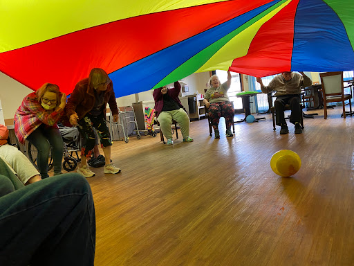 Participants engage in a fun and interactive game under a colorful parachute.