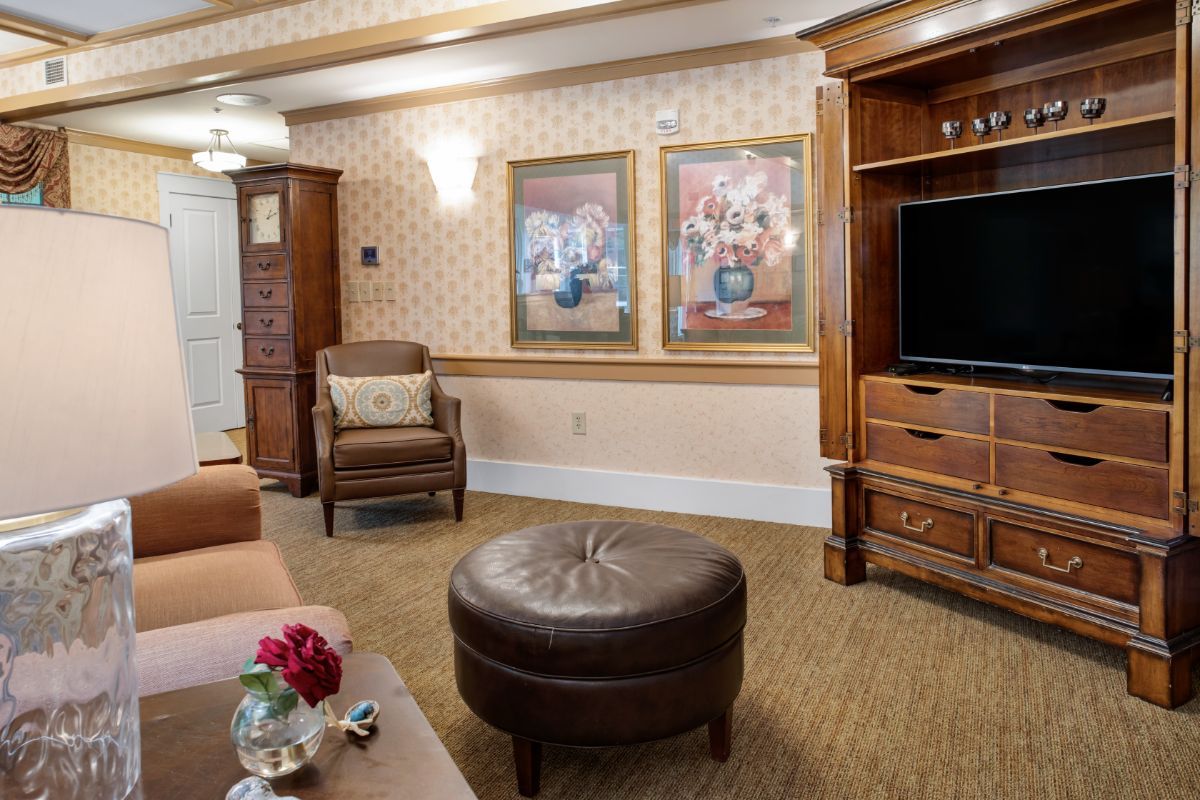 A cozy living room featuring comfortable chairs, a television, and artwork on the walls.
