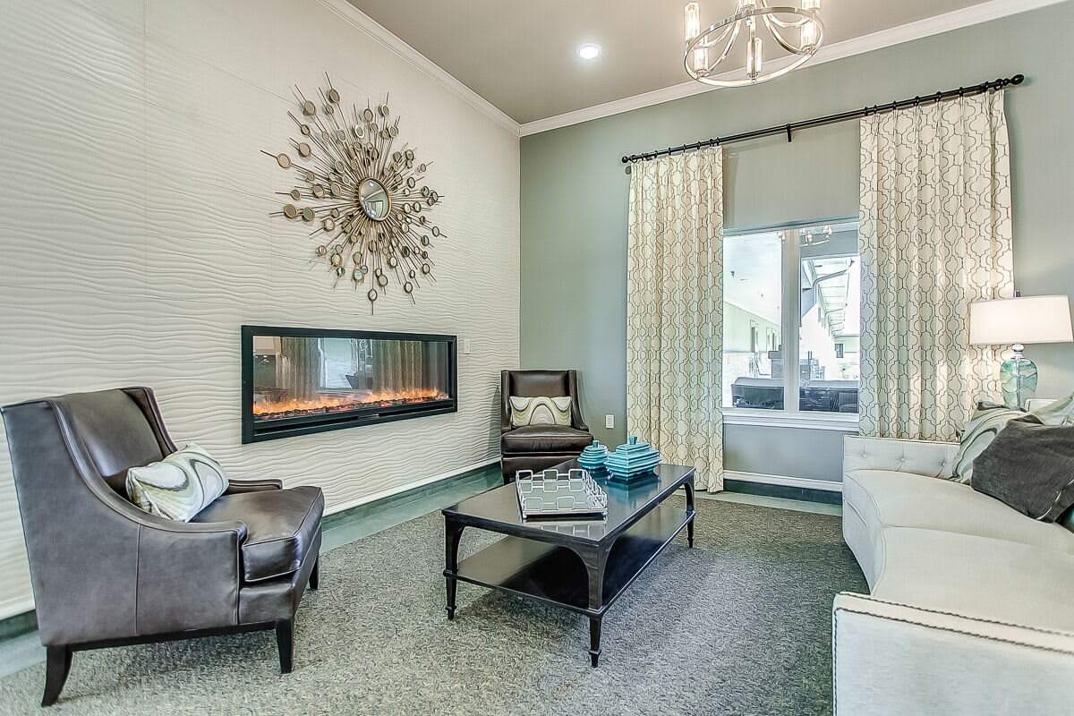 A modern living room featuring a sleek fireplace, elegant chandelier, and stylish wall art.